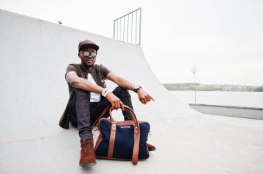 Şık Afro-Amerikan erkek giyimi sunglas üzerinde oturma portre