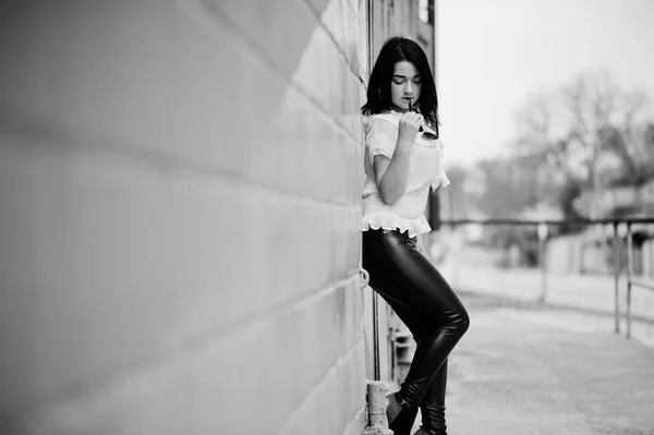 Portrait of  brunette girl on women's leather pants and white bl — Stock Photo, Image