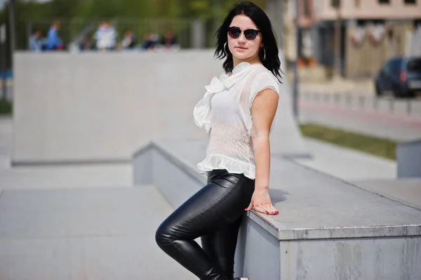 Brünettes Mädchen auf Lederhose und weißer Bluse, Sonnenbrille — Stockfoto