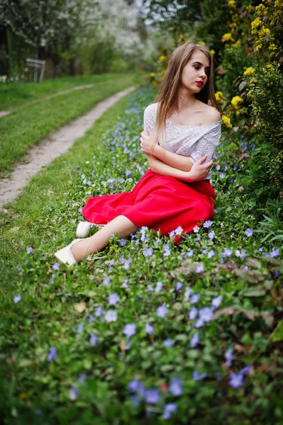 Retrato de sitiing menina bonita com lábios vermelhos na flor da primavera — Fotografia de Stock