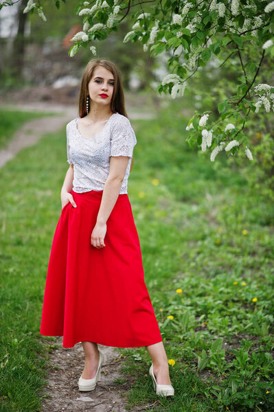 Portrait of beautiful girl with red lips at spring blossom garde