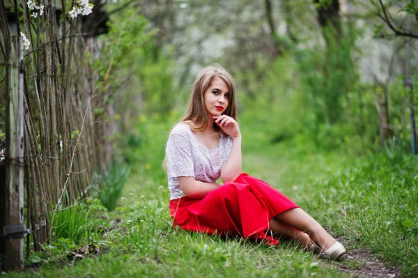 Retrato de sentada hermosa chica con labios rojos en la floración de primavera — Foto de Stock