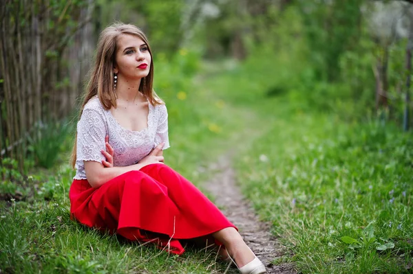 Retrato de sentada hermosa chica con labios rojos en la floración de primavera — Foto de Stock