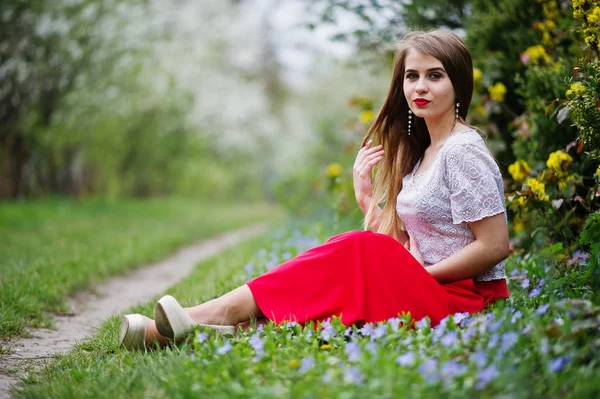 Retrato de sitiing menina bonita com lábios vermelhos na flor da primavera — Fotografia de Stock