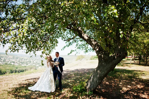 Happy wedding couple in love near trees on sunny day. — Stock Photo, Image