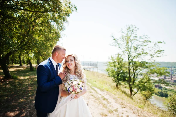 Happy wedding couple in love near trees on sunny day. — Stock Photo, Image