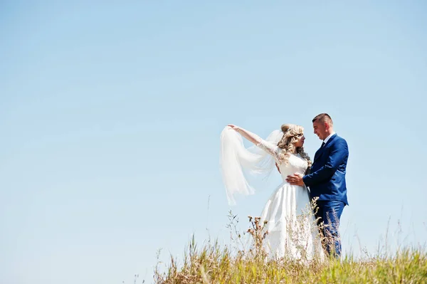 Verheugd huwelijksfeest paar verliefd op zonnige dag verblijf tegen blauwe hemel. — Stockfoto