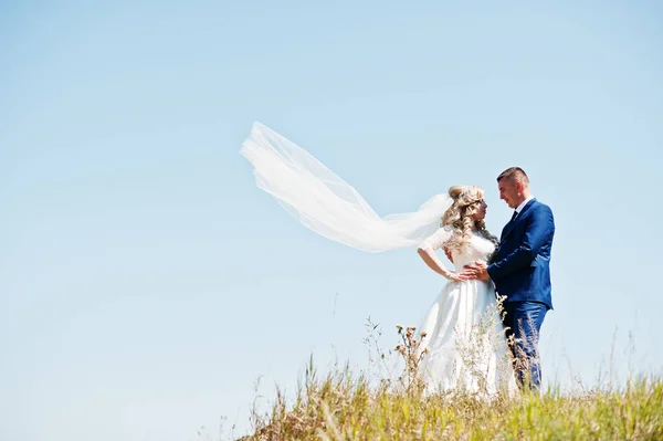 Verheugd huwelijksfeest paar verliefd op zonnige dag verblijf tegen blauwe hemel. — Stockfoto