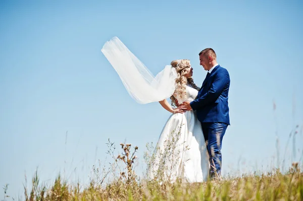 Glückliches verliebtes Hochzeitspaar am sonnigen Tag vor blauem Himmel. — Stockfoto