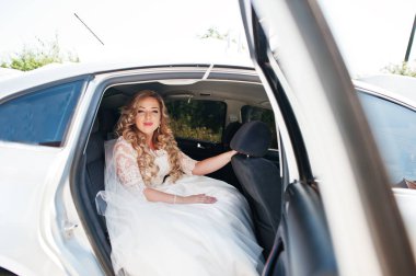 Güneşli gün araba üzerinde oturan güzel sarışın kıvırcık gelin.