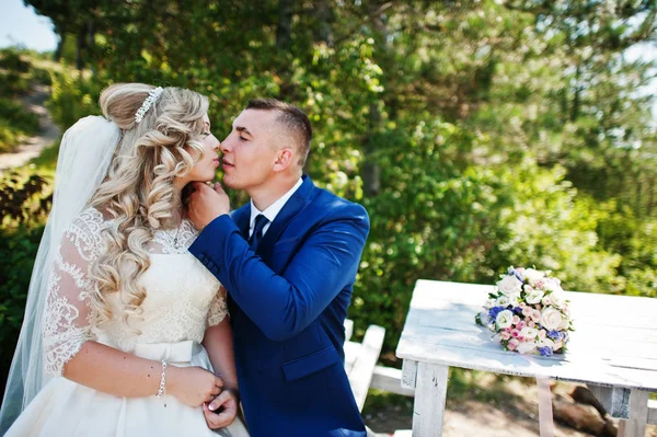 Casal de casamento feliz no amor no dia ensolarado sentado na mesa de madeira — Fotografia de Stock