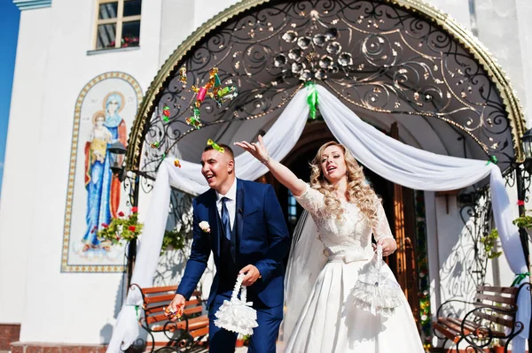 Pareja de boda lanzando caramelos después de la ceremonia de boda en la iglesia — Foto de Stock