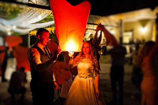 Wedding couple with air lanterns at evening wedding party outdoo — Stock Photo, Image