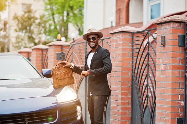 Stylish black man at glasses with hat, wear on suit with handbag