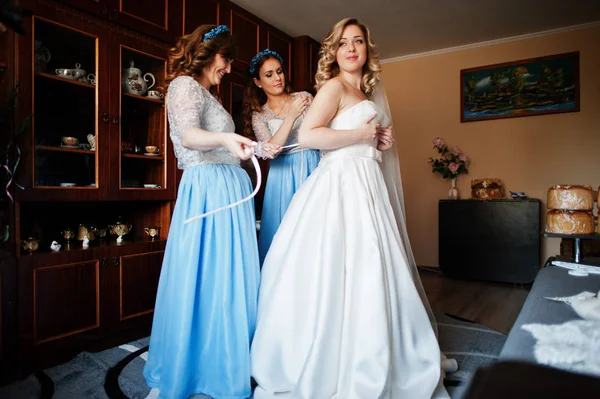 Bridesmaids and bride preparing at room on wedding morning.