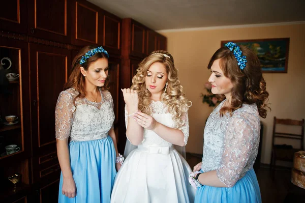 Bridesmaids and bride preparing at room on wedding morning.