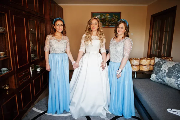 Bridesmaids and bride preparing at room on wedding morning.