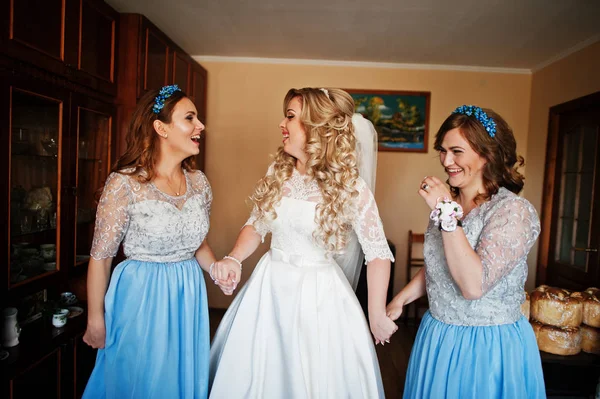 Bridesmaids and bride preparing at room on wedding morning.