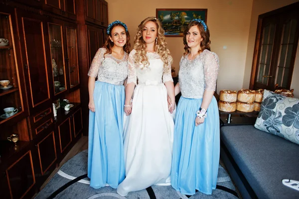 Bridesmaids and bride preparing at room on wedding morning.