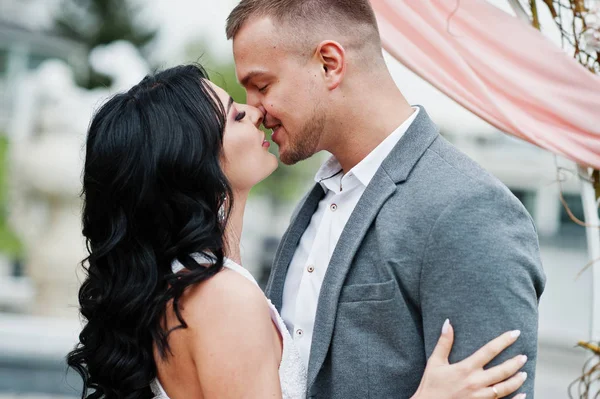 Giovane bella coppia baciata alla moda contro arco decorativo sul matrimonio — Foto Stock