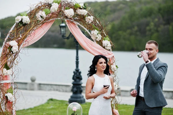 Joven pareja encantadora de moda contra arco de decoración en la boda un — Foto de Stock
