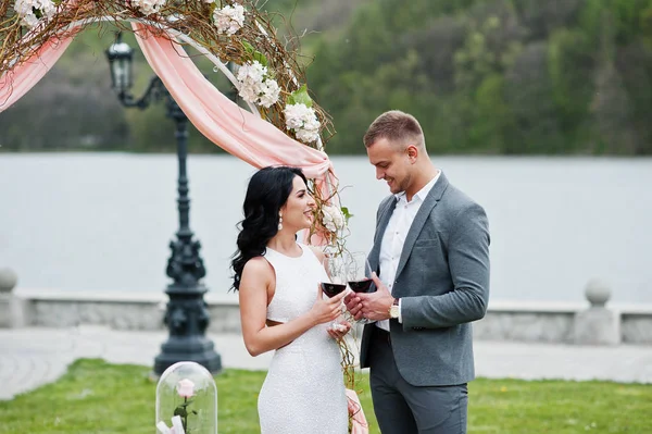 Joven pareja encantadora de moda contra arco de decoración en la boda un — Foto de Stock