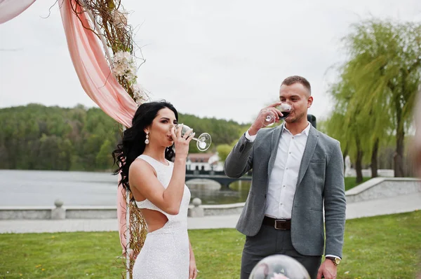 Joven pareja encantadora de moda contra arco de decoración en la boda un — Foto de Stock