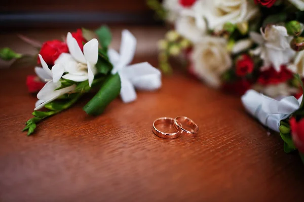 Wedding rings with bouquet and buttonhole on wooden background. — Stock Photo, Image