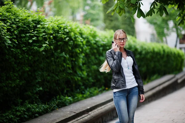 Stijlvolle blonde vrouw dragen op een jeans, bril en lederen jas w — Stockfoto