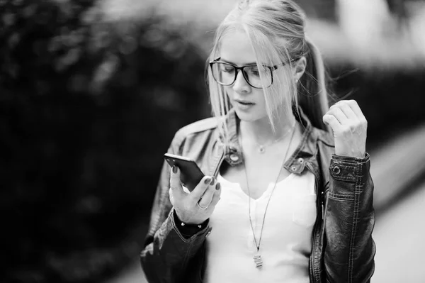 Стильная блондинка в джинсах, очках и кожаной куртке — стоковое фото