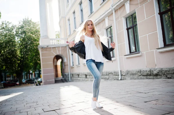 Stylische Blondine in Jeans, Sonnenbrille und Jacke posiert — Stockfoto