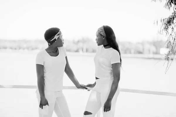 Две стильные и трогательные африканские девушки, одетые в белое платье — стоковое фото