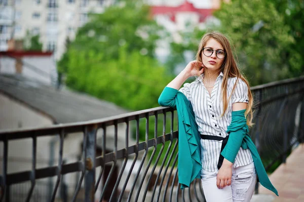 Chica de moda en gafas y pantalones vaqueros rasgados contra la barrera en stree —  Fotos de Stock