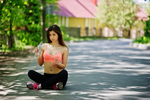 Chica de deporte de fitness en ropa deportiva sentado en la carretera en la calle y d — Foto de Stock