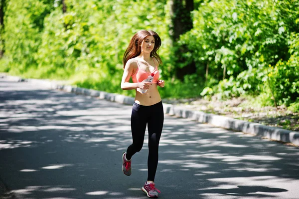 Fitness menina esporte em sportswear correr na estrada na floresta com bott — Fotografia de Stock