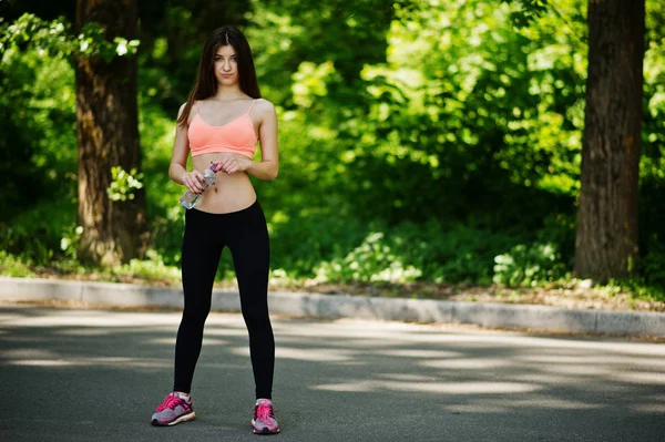 Fitness menina esporte em sportswear posou na estrada no parque com bott — Fotografia de Stock