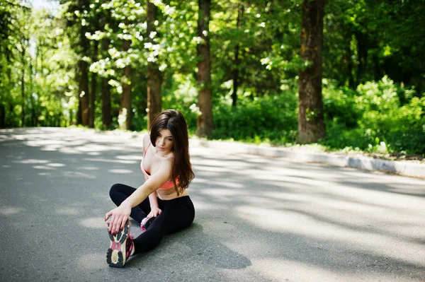 Девочка в спортивной одежде, сидящая на дороге в парке, перевернулась — стоковое фото