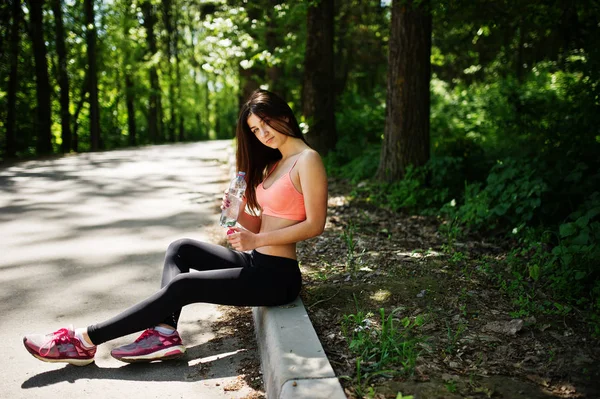 Fitness menina esporte em sportswear sentado na estrada no parque com wa — Fotografia de Stock