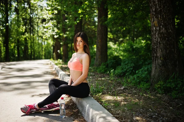 Chica de deporte de fitness en ropa deportiva sentado en la carretera en el parque con wa —  Fotos de Stock