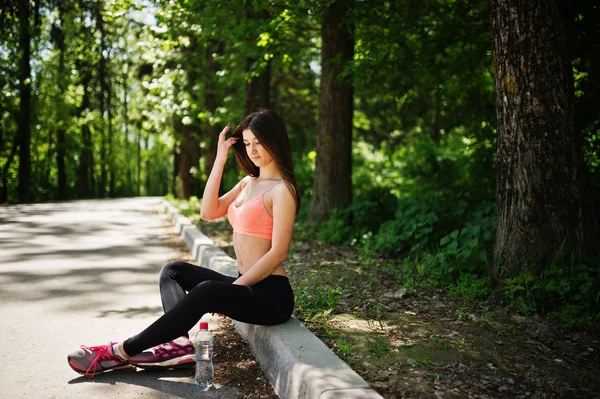 Chica de deporte de fitness en ropa deportiva sentado en la carretera en el parque con wa — Foto de Stock