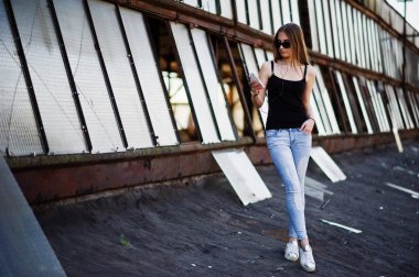 Güneş gözlüğü ve kot pantolon, telefon ve kulaklık ile kız, poz verdi