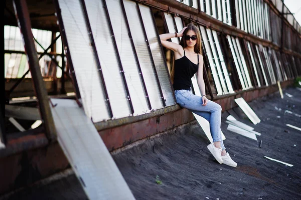 Девушка в солнцезащитных очках и джинсах позировала на крыше заброшенных индусов — стоковое фото