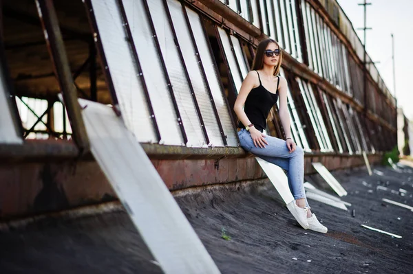 Menina em óculos de sol e jeans posou no telhado da indústria abadoned — Fotografia de Stock