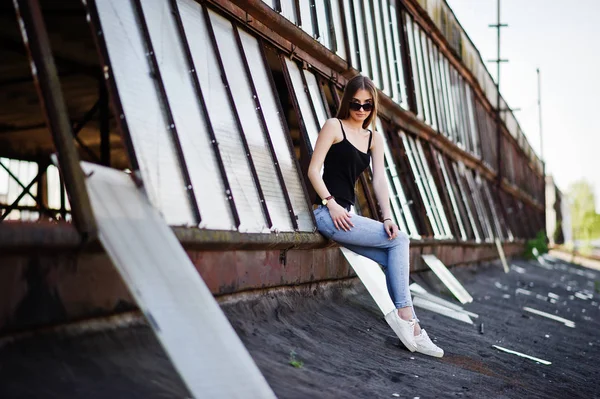 Gadis berkacamata hitam dan jeans berpose di atap indus abadoned — Stok Foto