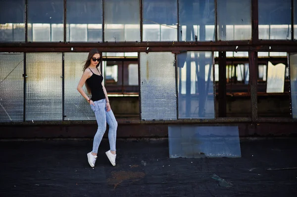 Flicka på solglasögon och jeans poserade på taket av abadoned indus — Stockfoto