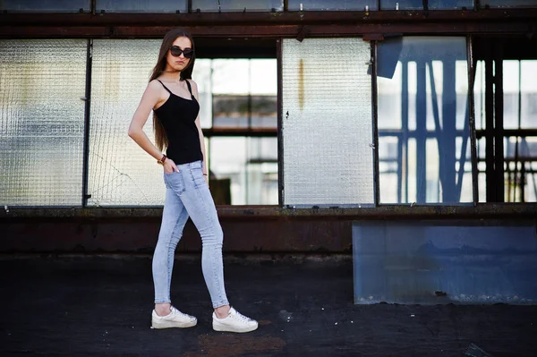 Дівчина в сонцезахисних окулярах і джинсах, позувала на даху камеонованого інду — стокове фото
