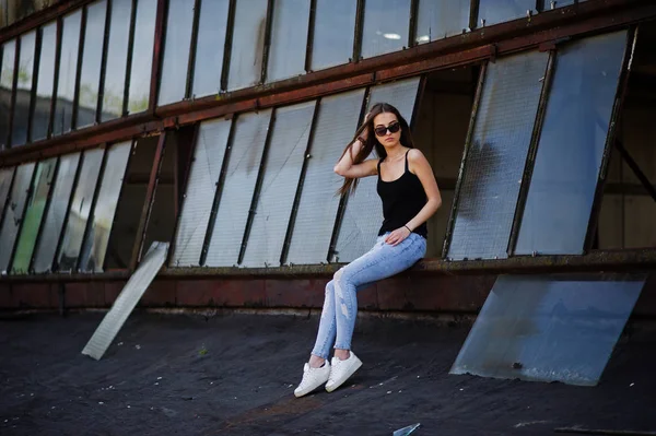 Fille à lunettes de soleil et jeans posés sur le toit des industries abadonnées — Photo