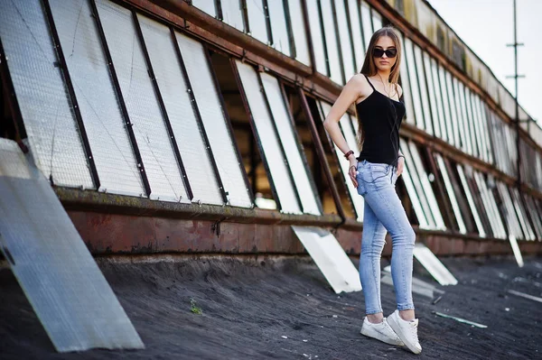 Chica en gafas de sol y jeans, con teléfono y auriculares posados en —  Fotos de Stock