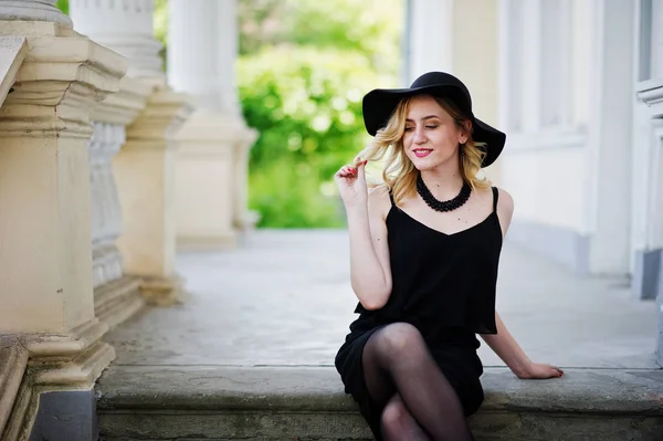 Mulher loira em vestido preto, colares e chapéu contra o vintage h — Fotografia de Stock
