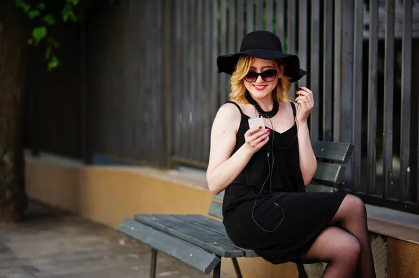 Femme blonde sur robe noire, lunettes de soleil, colliers et chapeau sitti — Photo